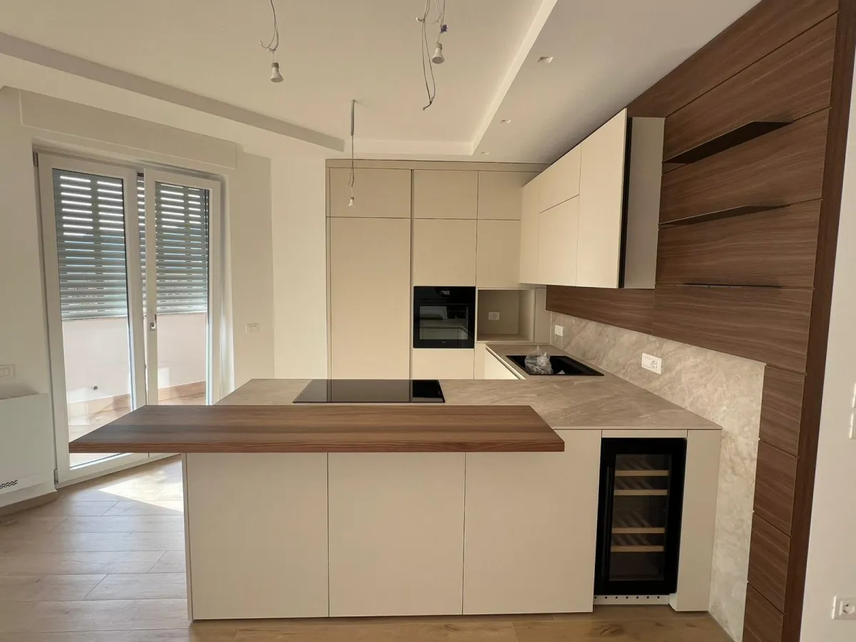 Cucina bianca con penisola e parete in noce con mensole